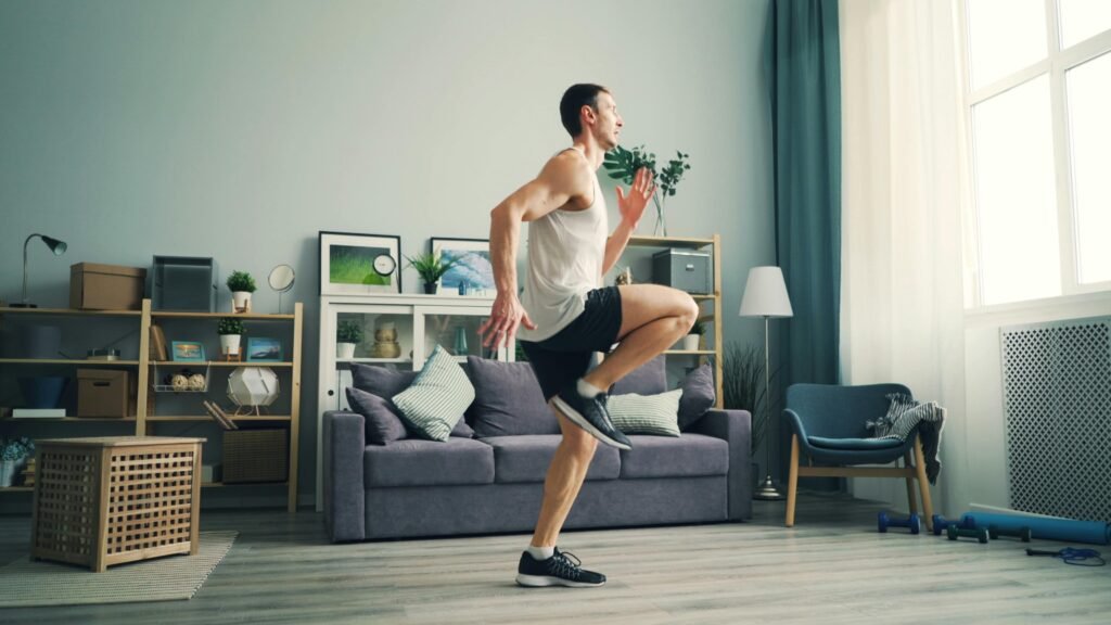 A man in sportswear exercising indoors with a modern living room background.
